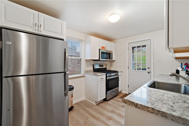 kitchen featuring light stone countertops, white cabinetry, sink, and appliances with stainless steel finishes