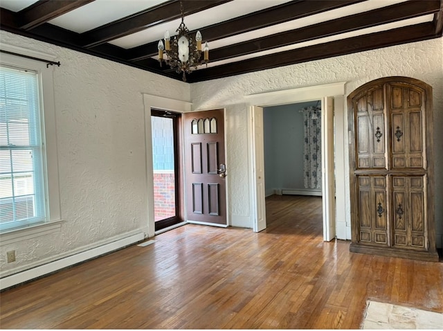 interior space featuring hardwood / wood-style flooring, a notable chandelier, beam ceiling, and a baseboard heating unit