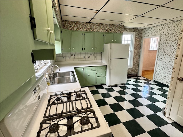 kitchen with a drop ceiling, green cabinets, white appliances, and sink