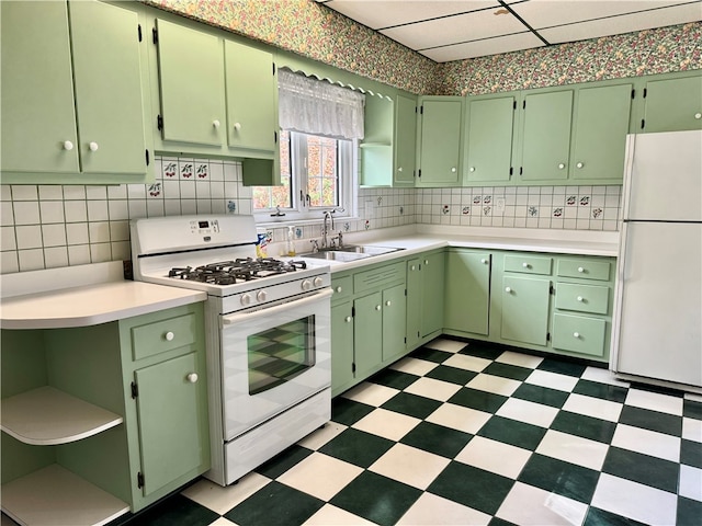 kitchen featuring backsplash, a paneled ceiling, white appliances, sink, and green cabinetry