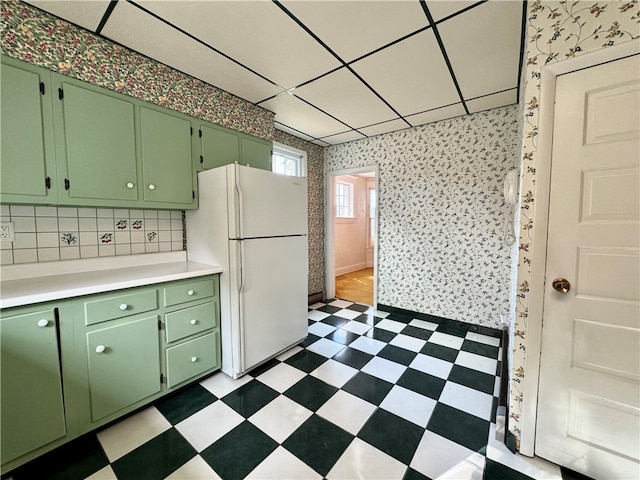 kitchen featuring a paneled ceiling, white refrigerator, and green cabinetry