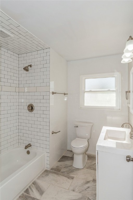 full bathroom featuring toilet, vanity, and tiled shower / bath