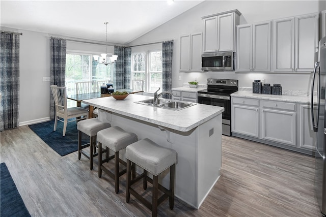 kitchen with appliances with stainless steel finishes, sink, a center island with sink, light hardwood / wood-style flooring, and lofted ceiling