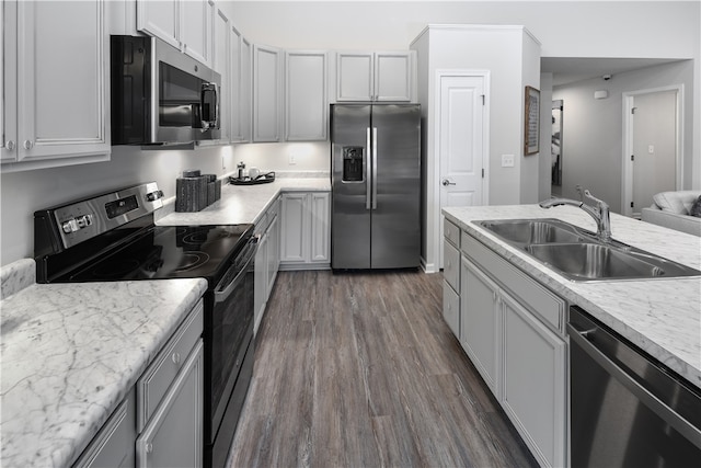 kitchen featuring stainless steel appliances, light stone counters, dark hardwood / wood-style floors, and sink