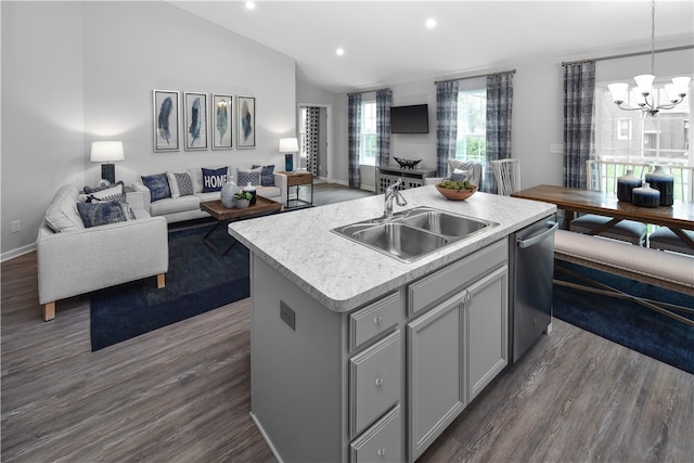 kitchen featuring dishwasher, sink, vaulted ceiling, decorative light fixtures, and a center island with sink