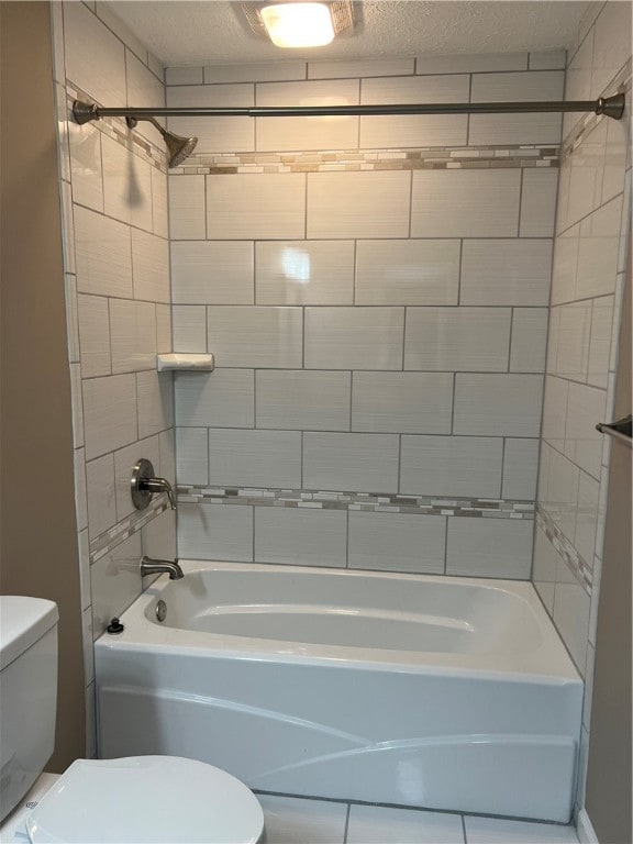 bathroom featuring a textured ceiling, toilet, and tiled shower / bath