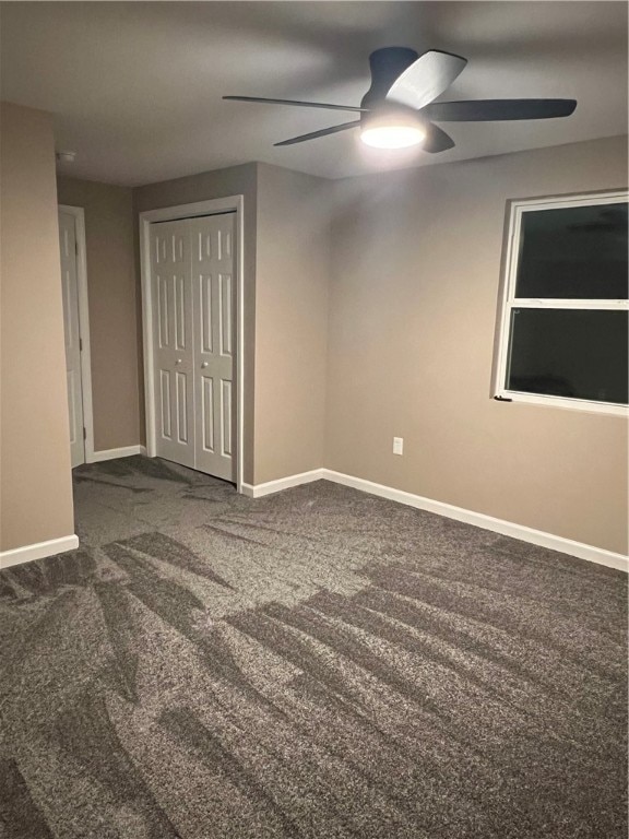 unfurnished room featuring dark colored carpet and ceiling fan