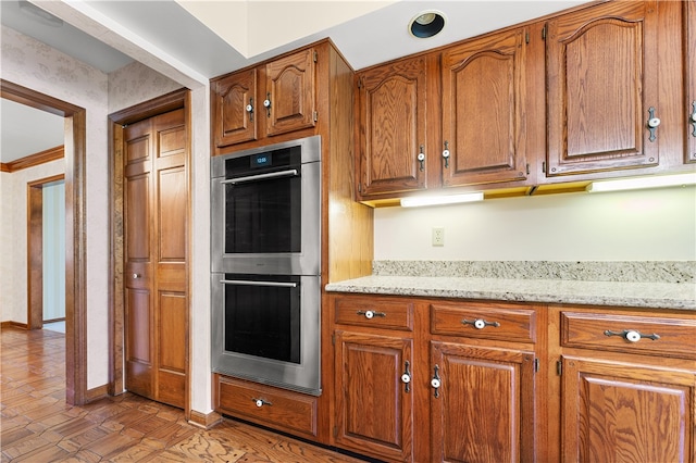 kitchen featuring light stone countertops, double oven, and light hardwood / wood-style flooring