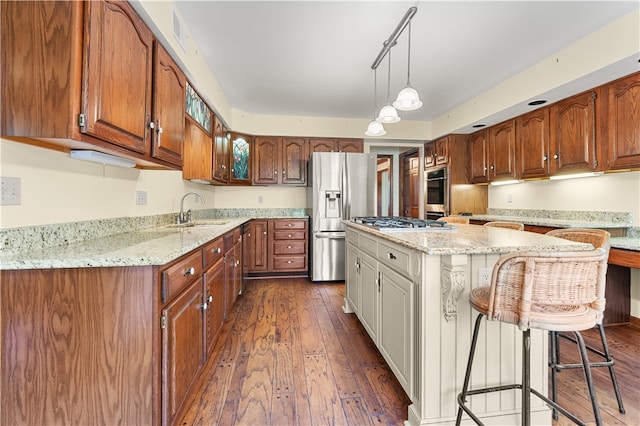 kitchen with light stone counters, stainless steel appliances, sink, dark hardwood / wood-style floors, and a kitchen island