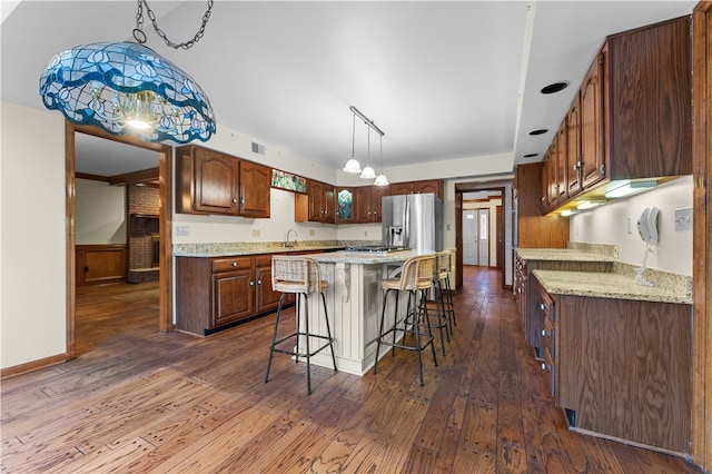 kitchen with stainless steel fridge with ice dispenser, dark hardwood / wood-style flooring, a center island, and light stone counters