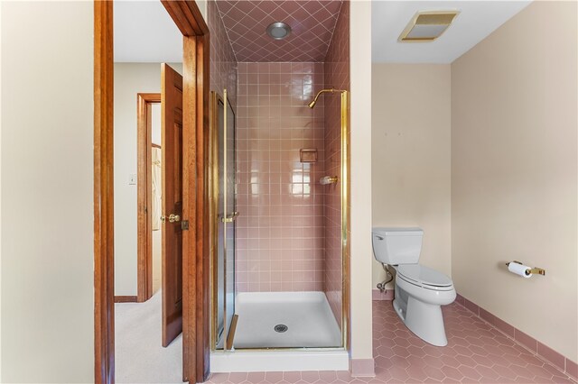 bathroom featuring tile patterned floors, a shower with shower door, and toilet