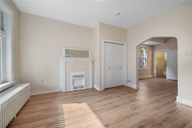 unfurnished living room featuring radiator heating unit and light hardwood / wood-style floors