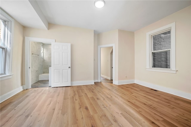 unfurnished bedroom with ensuite bathroom and light hardwood / wood-style floors