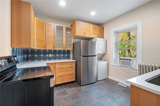 kitchen featuring radiator, stacked washer and dryer, stainless steel appliances, and light brown cabinets