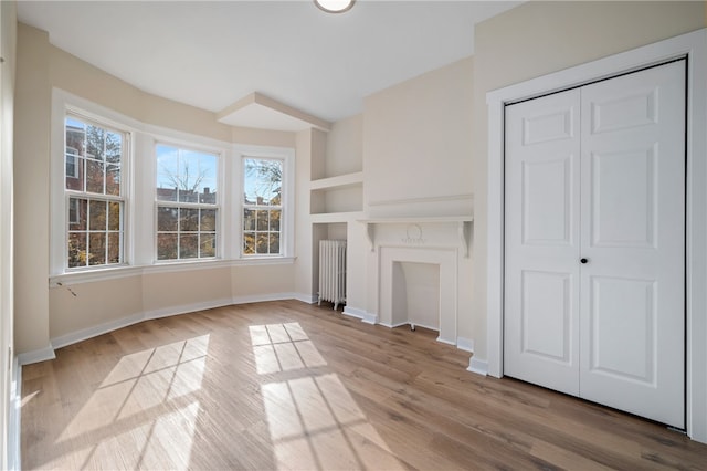 unfurnished living room featuring radiator heating unit and light hardwood / wood-style floors