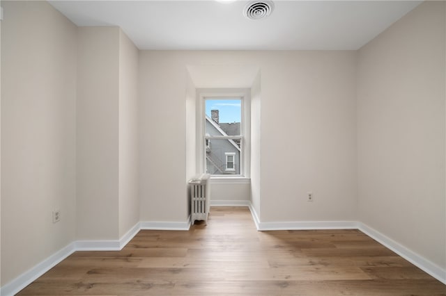 unfurnished room featuring light hardwood / wood-style floors and radiator