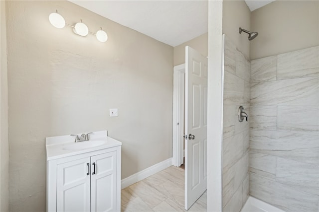 bathroom with tiled shower and vanity