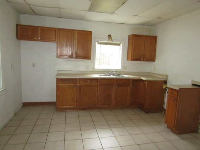 kitchen featuring a paneled ceiling, sink, and light tile patterned floors