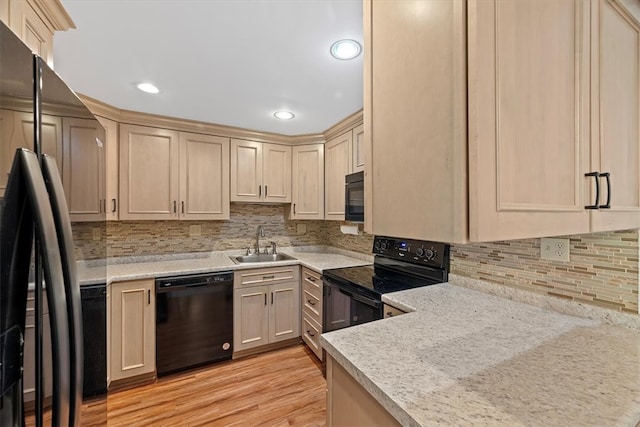 kitchen featuring backsplash, black appliances, sink, light wood-type flooring, and light stone counters