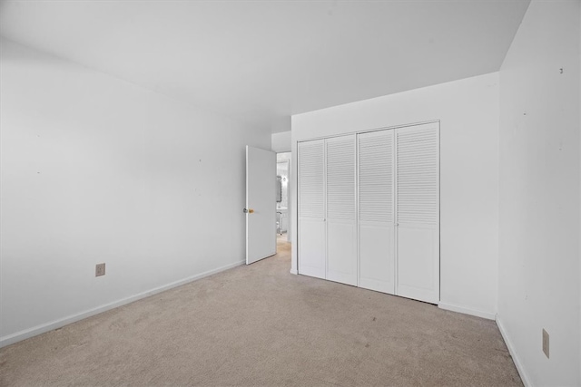 unfurnished bedroom with light colored carpet and a closet