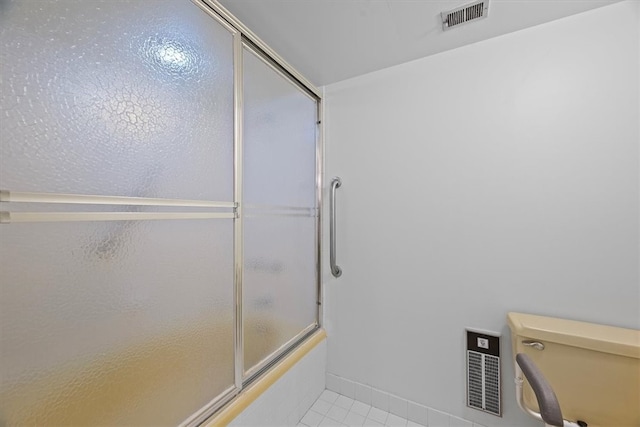 bathroom featuring tile patterned flooring, toilet, and enclosed tub / shower combo