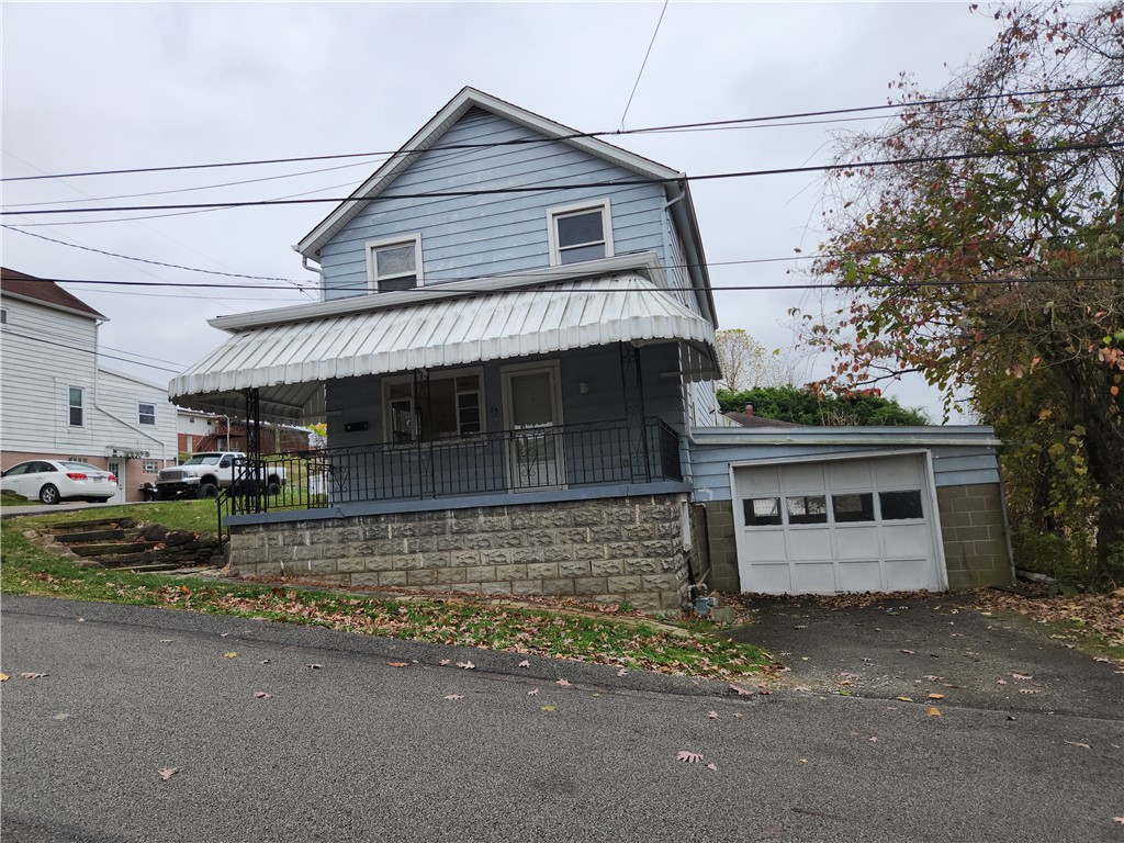 view of front facade featuring covered porch, a garage, and an outdoor structure