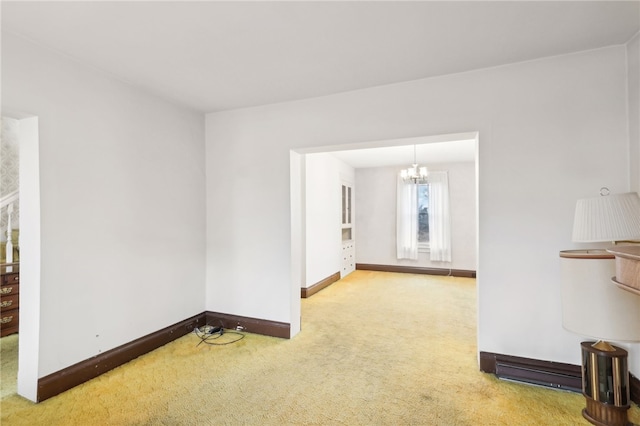 carpeted spare room featuring a chandelier