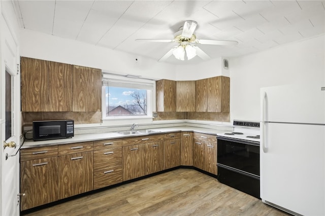 kitchen with hardwood / wood-style floors, white appliances, ceiling fan, and sink