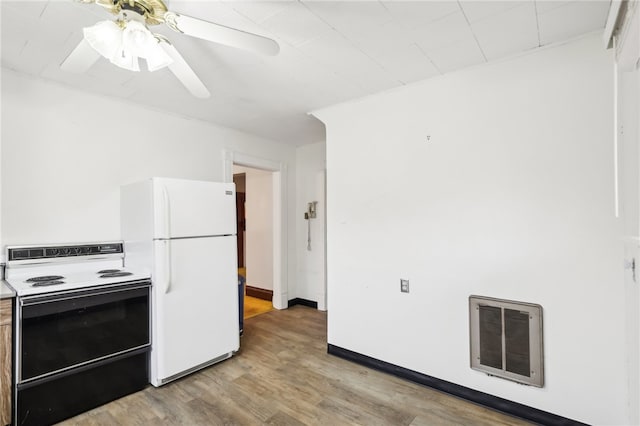 kitchen featuring white appliances, light hardwood / wood-style floors, heating unit, and ceiling fan