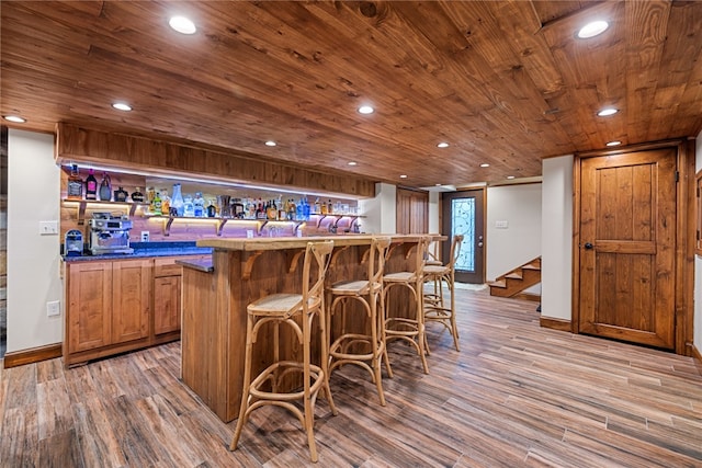 kitchen with a breakfast bar, light hardwood / wood-style flooring, and wood ceiling