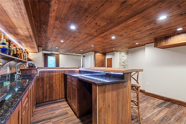 bar with dark stone counters, wooden ceiling, sink, and dark wood-type flooring