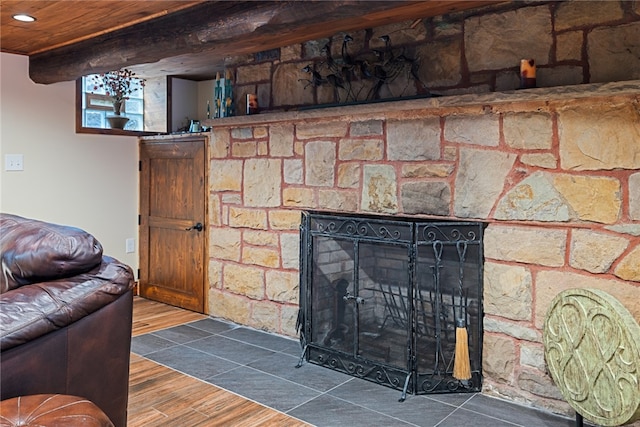 living room with beam ceiling, a stone fireplace, and dark wood-type flooring