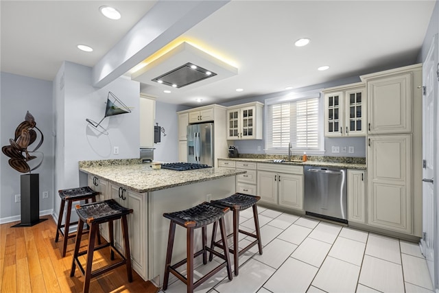 kitchen with sink, light hardwood / wood-style floors, a kitchen bar, kitchen peninsula, and stainless steel appliances