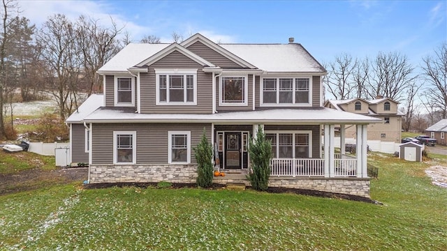 view of front of house featuring a front yard, a porch, and a storage shed