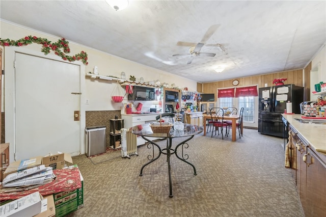 interior space with ceiling fan, crown molding, light colored carpet, and wood walls