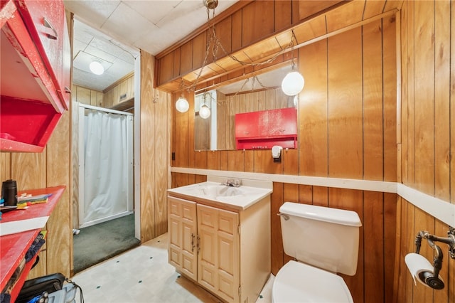 bathroom featuring vanity, wood walls, and toilet