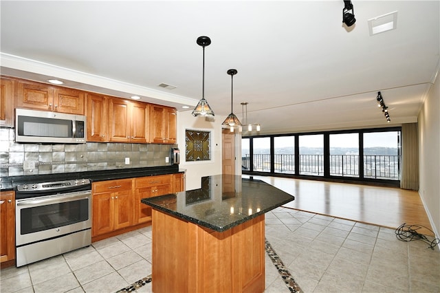 kitchen featuring a center island, backsplash, hanging light fixtures, appliances with stainless steel finishes, and a breakfast bar area