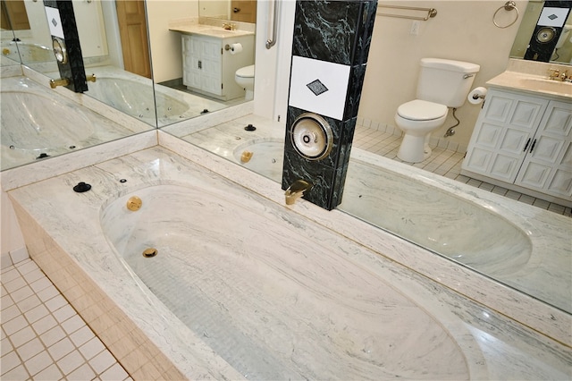 bathroom with tile patterned floors, vanity, a relaxing tiled tub, and toilet