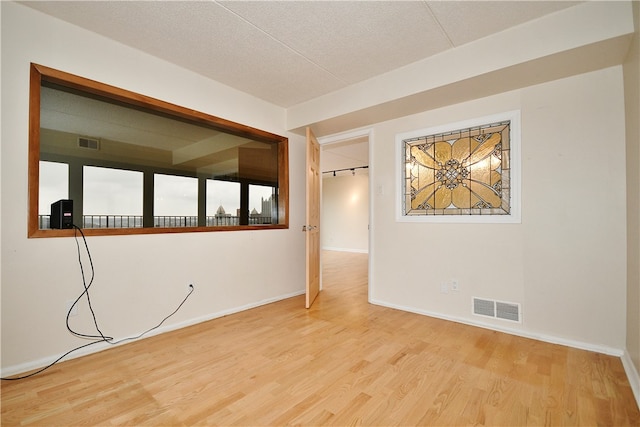 unfurnished room featuring light hardwood / wood-style floors and a textured ceiling