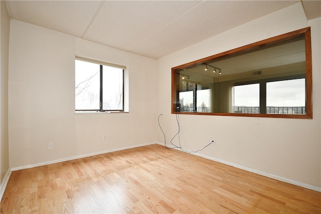 spare room with light hardwood / wood-style floors and a textured ceiling