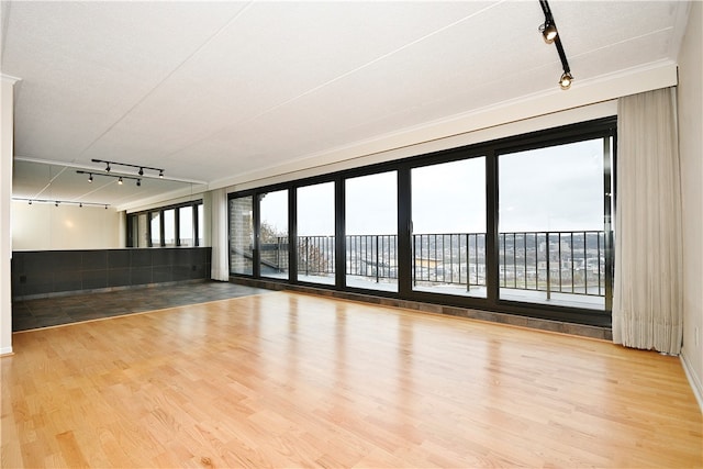 spare room with a textured ceiling, hardwood / wood-style floors, and track lighting