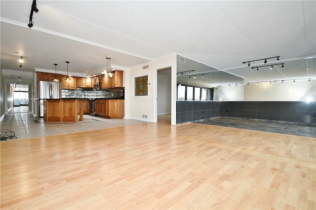 unfurnished living room featuring light hardwood / wood-style floors, crown molding, and track lighting