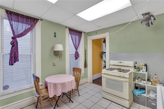 kitchen with light tile patterned floors, a paneled ceiling, and gas range gas stove