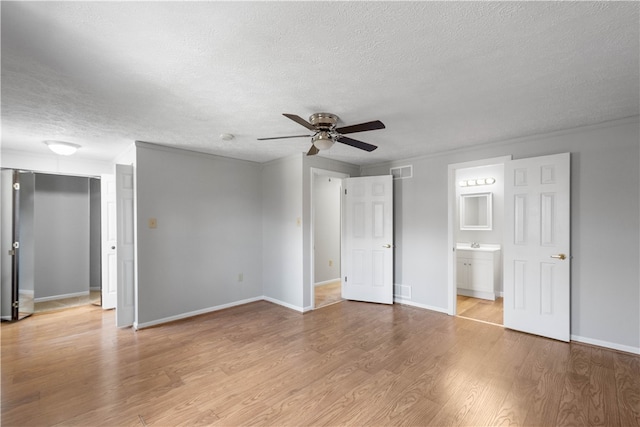 interior space featuring a textured ceiling, ceiling fan, light hardwood / wood-style floors, and ensuite bath