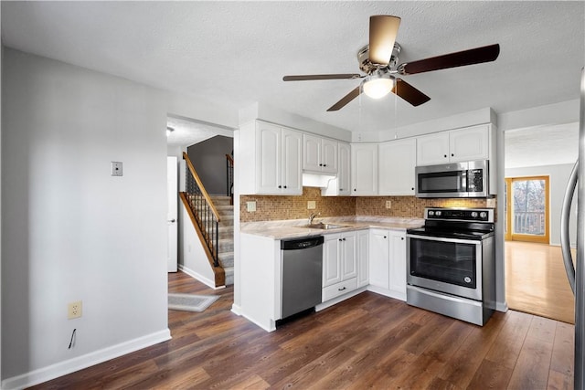 kitchen with appliances with stainless steel finishes, white cabinetry, backsplash, dark hardwood / wood-style floors, and ceiling fan