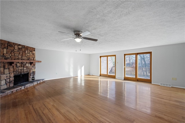 unfurnished living room with ceiling fan, a textured ceiling, light hardwood / wood-style flooring, and a fireplace