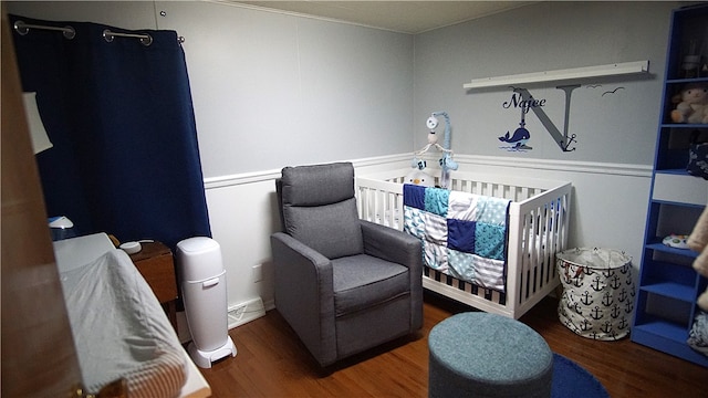 bedroom featuring dark wood-type flooring and a nursery area