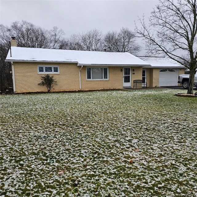 view of front of house featuring an attached garage, brick siding, and a chimney