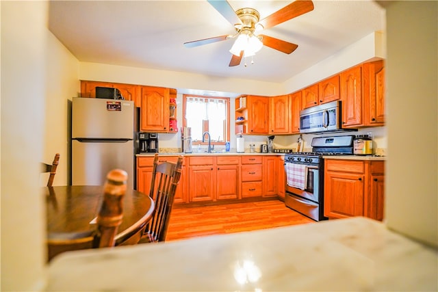 kitchen featuring appliances with stainless steel finishes, light hardwood / wood-style flooring, ceiling fan, and sink