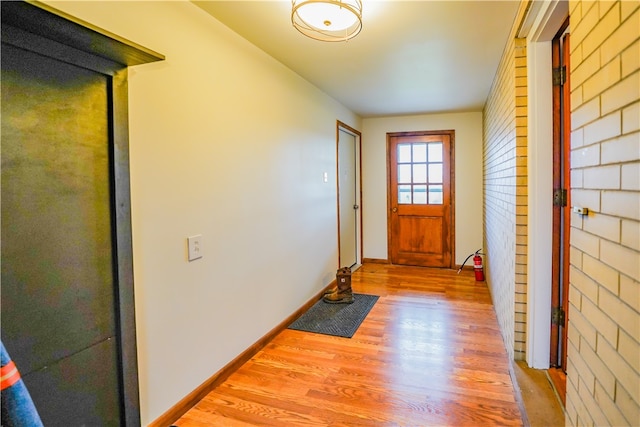 doorway featuring light hardwood / wood-style floors and brick wall